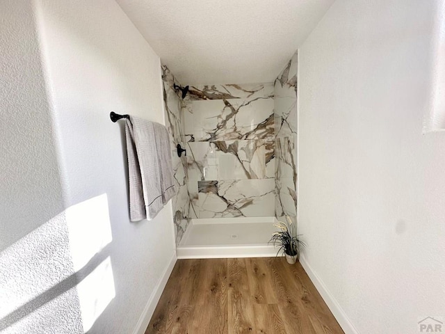 bathroom with baseboards, a shower, and wood finished floors