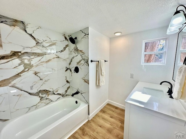 bathroom with a textured ceiling,  shower combination, wood finished floors, and vanity