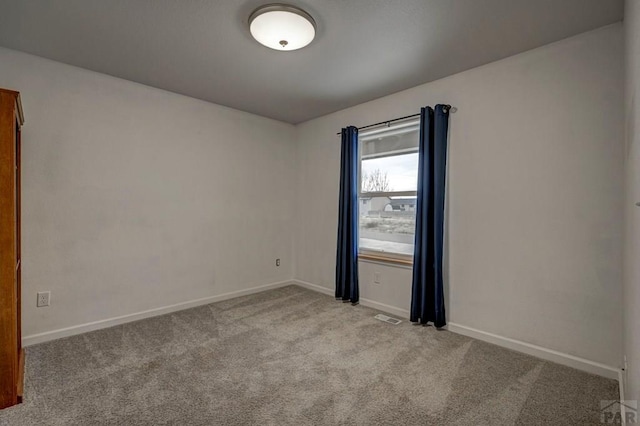 spare room featuring baseboards and light colored carpet