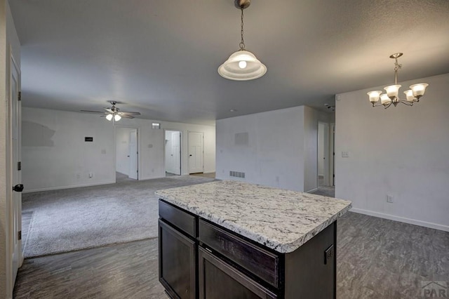 kitchen with a kitchen island, open floor plan, light countertops, dark brown cabinets, and pendant lighting