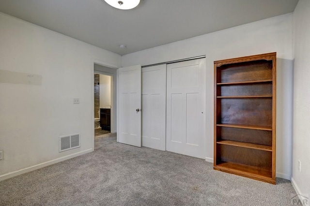 unfurnished bedroom with a closet, visible vents, light carpet, and baseboards