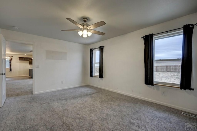 spare room featuring carpet floors, a ceiling fan, visible vents, and baseboards