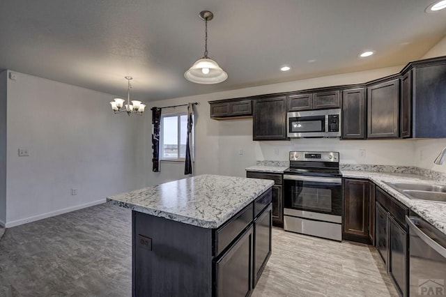 kitchen featuring decorative light fixtures, a center island, stainless steel appliances, a sink, and recessed lighting