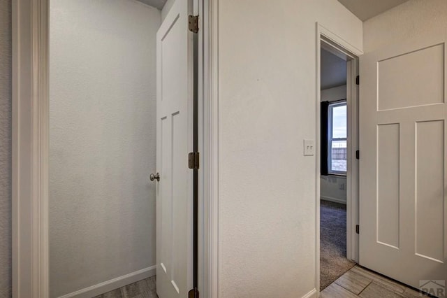 corridor with light wood-style flooring and baseboards