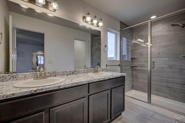 full bath with double vanity, a stall shower, and a sink