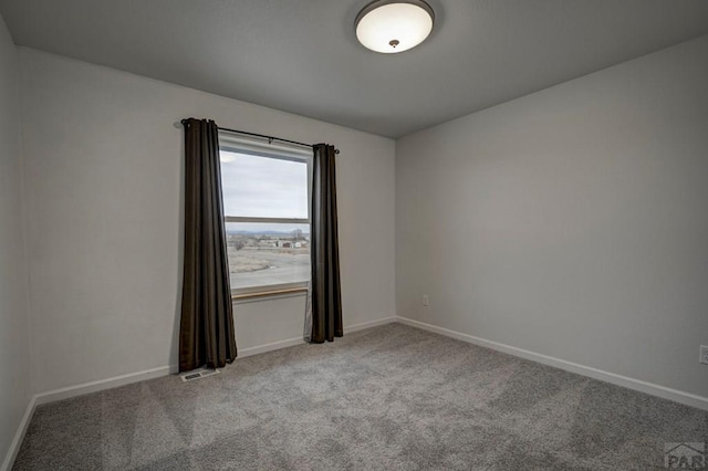 carpeted spare room with visible vents and baseboards