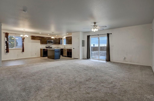 unfurnished living room with baseboards, light colored carpet, ceiling fan with notable chandelier, a sink, and recessed lighting