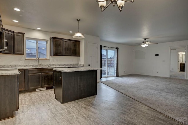 kitchen with dark brown cabinetry, open floor plan, a center island, decorative light fixtures, and a sink