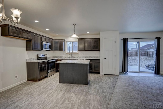 kitchen featuring a center island, decorative light fixtures, appliances with stainless steel finishes, a sink, and light stone countertops