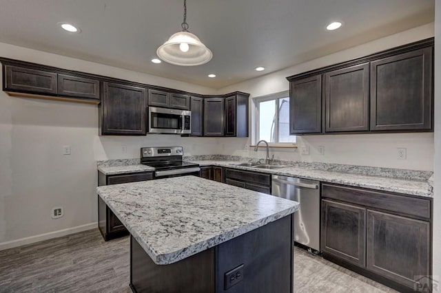 kitchen with dark brown cabinetry, a kitchen island, appliances with stainless steel finishes, pendant lighting, and a sink