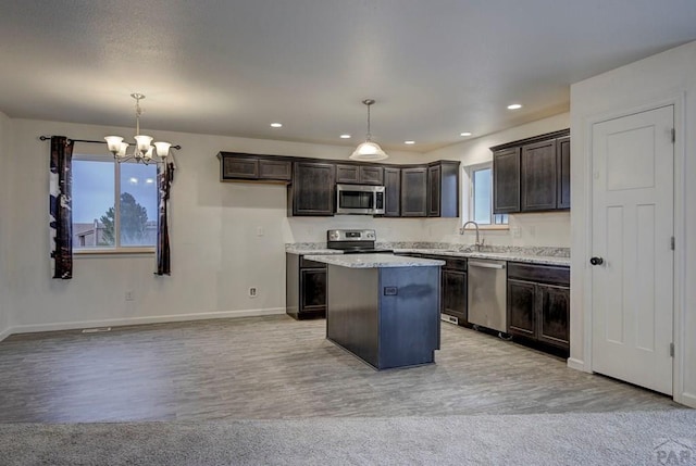 kitchen featuring dark brown cabinetry, a kitchen island, appliances with stainless steel finishes, and pendant lighting