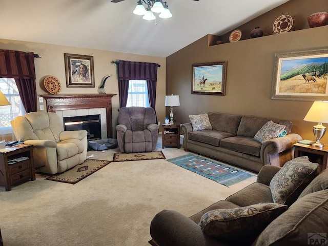 living area with ceiling fan, lofted ceiling, carpet floors, and a tile fireplace