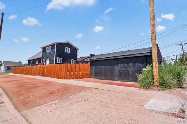 view of property exterior with an outdoor structure and fence