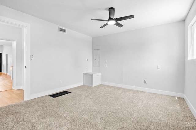 unfurnished room with baseboards, electric panel, a ceiling fan, visible vents, and light colored carpet