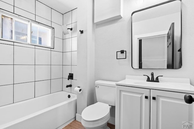 bathroom featuring vanity, wood finished floors, toilet, and shower / washtub combination