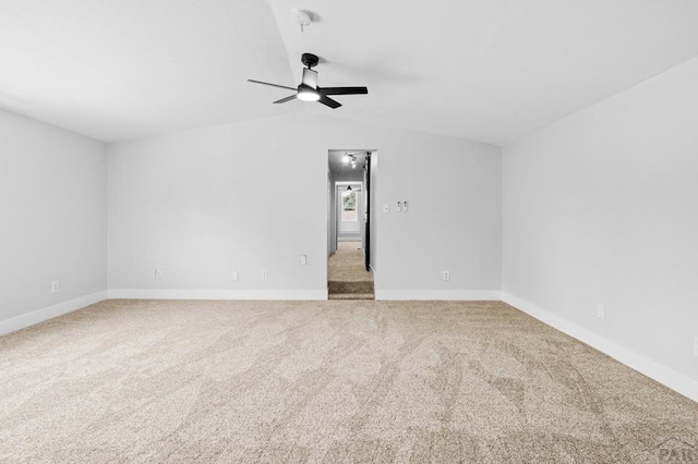 carpeted empty room featuring baseboards, vaulted ceiling, and a ceiling fan