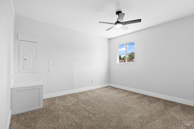 carpeted empty room featuring baseboards, a ceiling fan, and electric panel