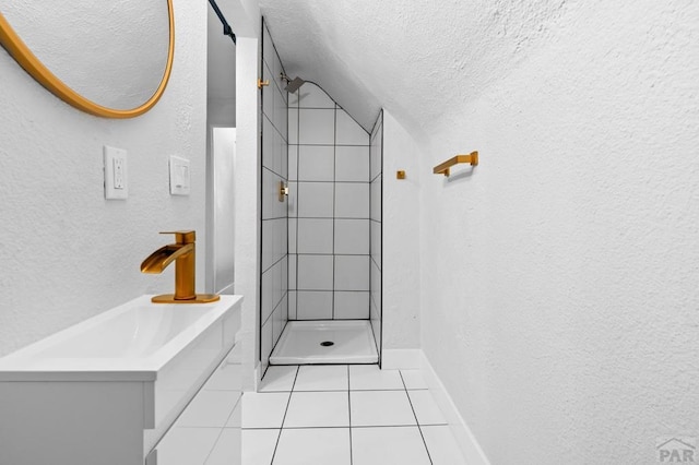 full bath with a textured wall, tile patterned floors, a textured ceiling, tiled shower, and a sink