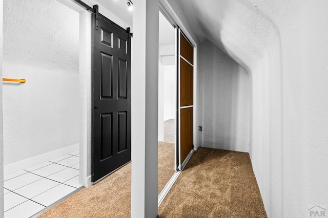 corridor with carpet flooring, a barn door, and a textured ceiling