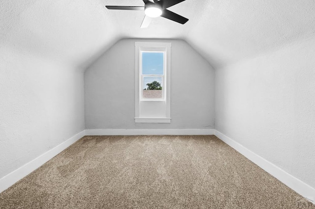 additional living space with a ceiling fan, carpet flooring, vaulted ceiling, and a textured ceiling