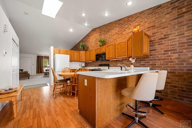 2106 Chatalet Ln Unit I, Pueblo, CO 81005 - kitchen with black microwave, electric range oven, freestanding refrigerator, light wood-style flooring, and vaulted ceiling
