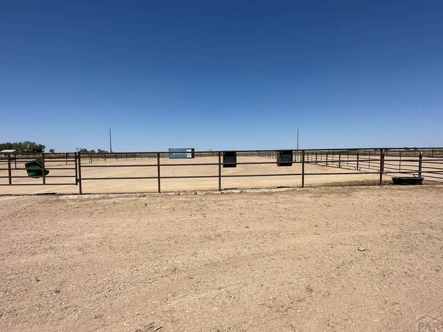 view of yard with an enclosed area, a rural view, and fence