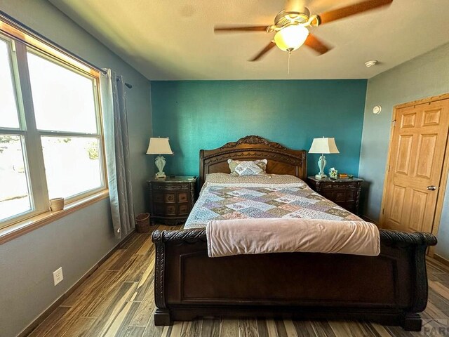 bedroom featuring ceiling fan, baseboards, and wood finished floors