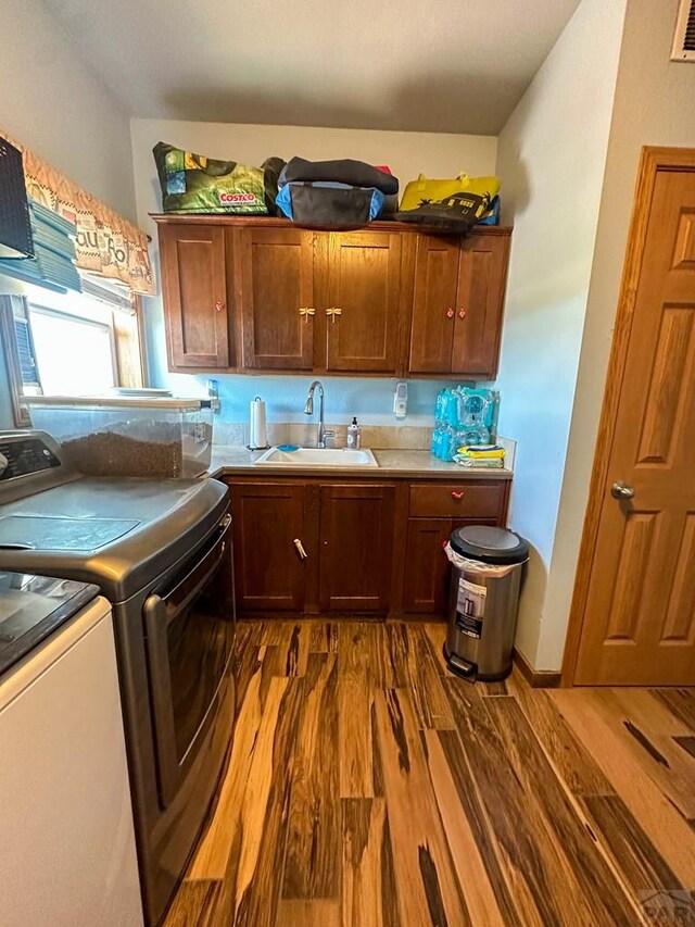 kitchen featuring dark wood-style flooring, visible vents, a sink, and washing machine and clothes dryer