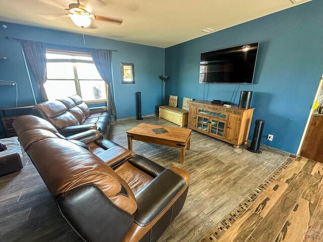 living room featuring visible vents, ceiling fan, baseboards, and wood finished floors