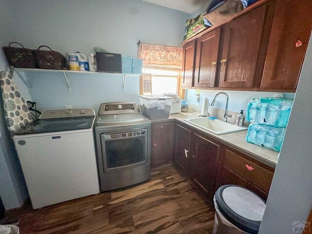 laundry room featuring washing machine and clothes dryer, cabinet space, a sink, and dark wood finished floors