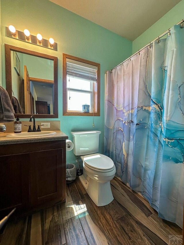 full bath featuring a shower with curtain, vanity, toilet, and wood finished floors