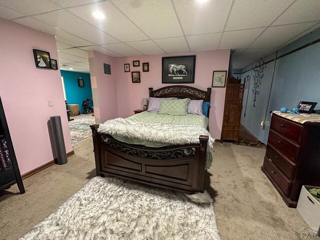 bedroom featuring a paneled ceiling, light carpet, and baseboards