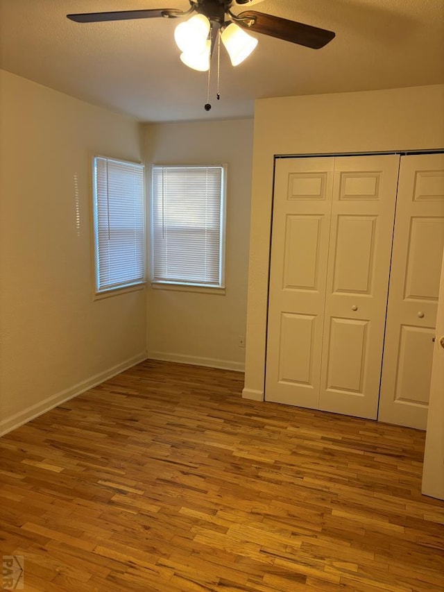 unfurnished bedroom featuring a ceiling fan, light wood-type flooring, a closet, and baseboards