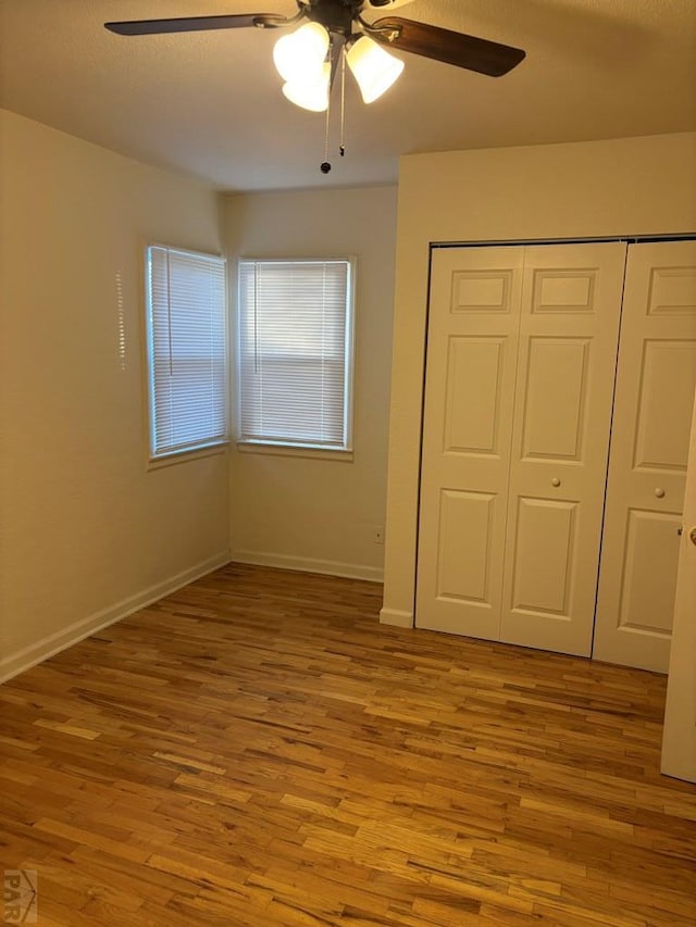 unfurnished bedroom featuring light wood-style floors, a closet, ceiling fan, and baseboards