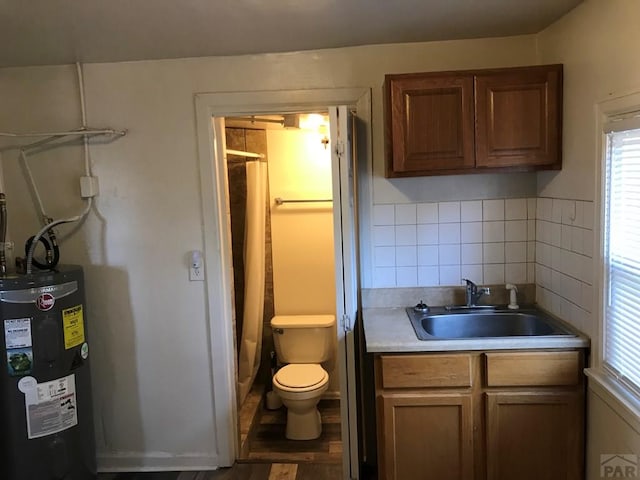 bathroom featuring tasteful backsplash, water heater, a sink, and toilet