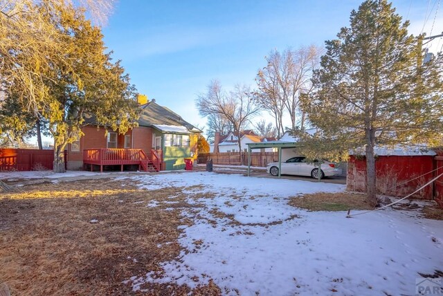 yard covered in snow with fence and a wooden deck