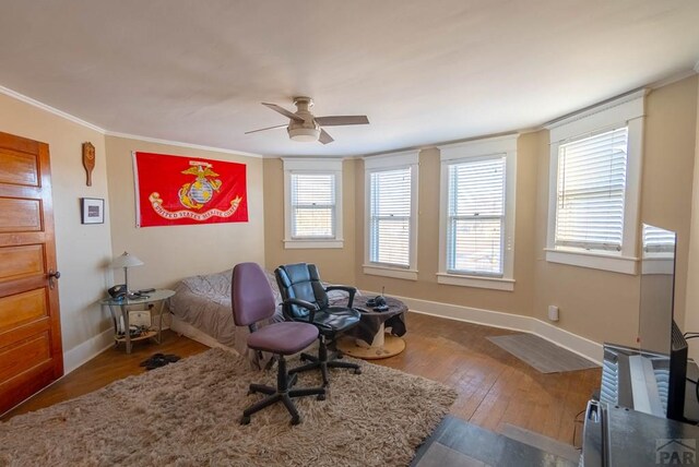 bedroom featuring a ceiling fan, crown molding, baseboards, and wood finished floors