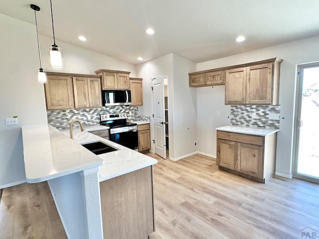 kitchen with a peninsula, appliances with stainless steel finishes, a sink, and a healthy amount of sunlight