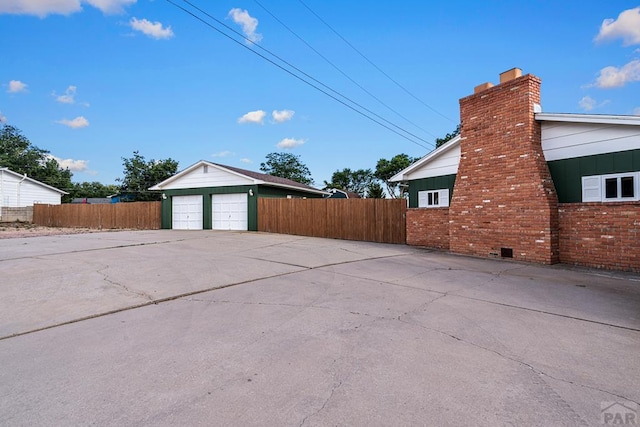 3216 Baltimore Ave, Pueblo, CO 81008 - view of side of property featuring a chimney, board and batten siding, brick siding, an outdoor structure, and a detached garage