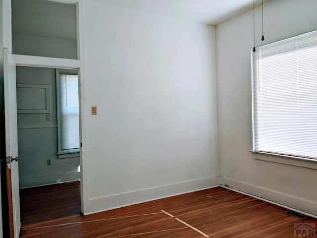 unfurnished room featuring dark wood-style floors, baseboards, and visible vents