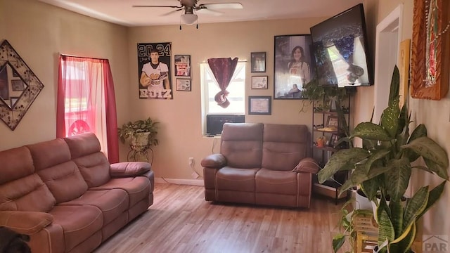 living area featuring ceiling fan, baseboards, and wood finished floors