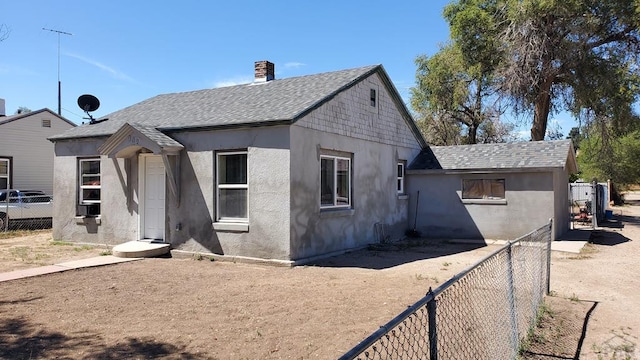 view of front of home featuring a shingled roof, fence, and stucco siding