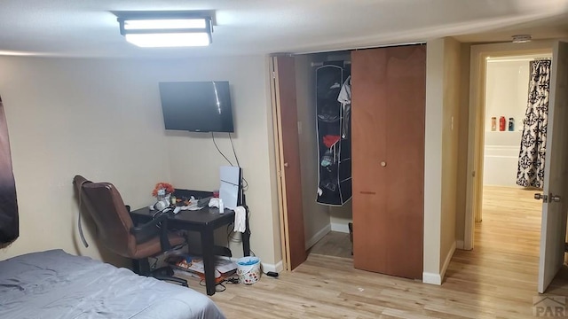 bedroom featuring a closet, light wood-style flooring, and baseboards