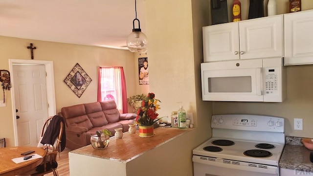 kitchen with white appliances, white cabinetry, open floor plan, and decorative light fixtures