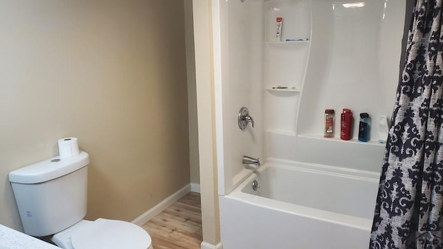 full bath featuring shower / tub combo with curtain, wood finished floors, toilet, and baseboards