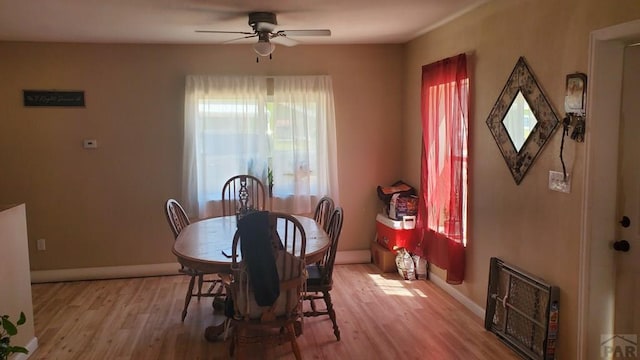 dining area with light wood-style floors, heating unit, ceiling fan, and baseboards