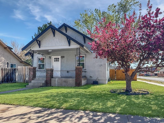view of front of home featuring a front yard, fence, and covered porch