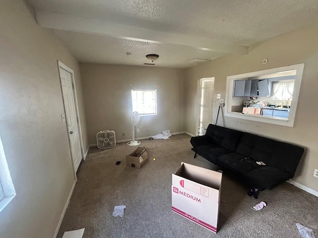 carpeted living room with a textured ceiling, baseboards, and beamed ceiling