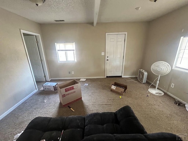 carpeted living room featuring plenty of natural light, a textured ceiling, baseboards, and beamed ceiling