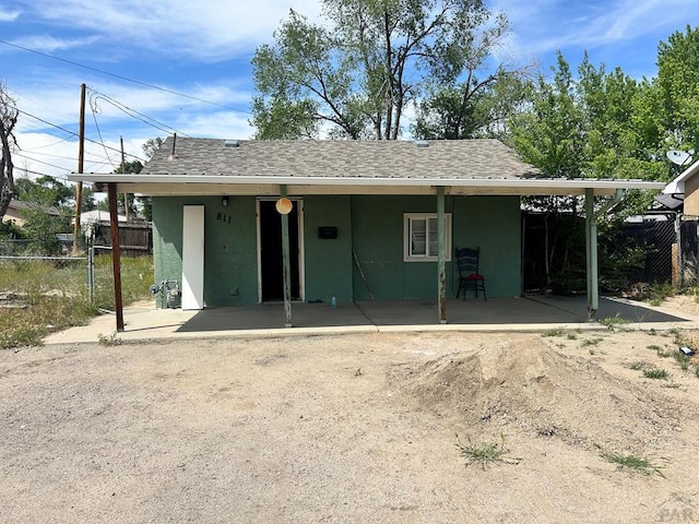 rear view of house with fence, stucco siding, and a shingled roof